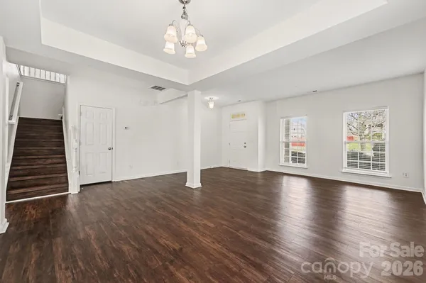 a view of an empty room with wooden floor and window
