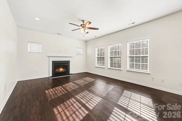 a view of an empty room with wooden floor fireplace and a window