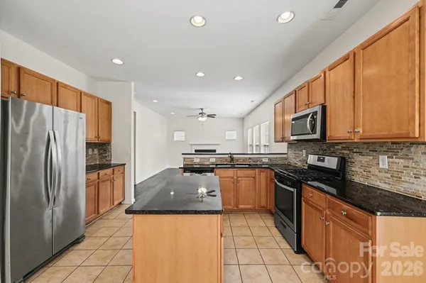 a large kitchen with stainless steel appliances granite countertop a refrigerator a stove top oven and a sink