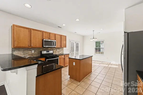 a kitchen with stainless steel appliances granite countertop a refrigerator stove top oven and sink