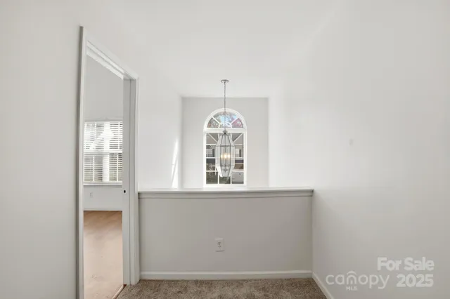 an empty room with a chandelier fan and windows