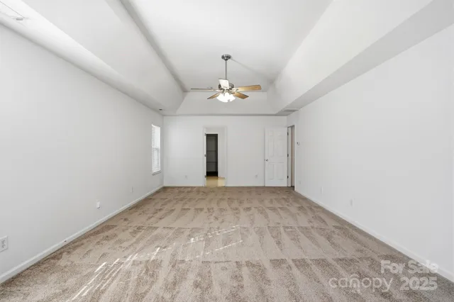 a view of an empty room with a chandelier fan