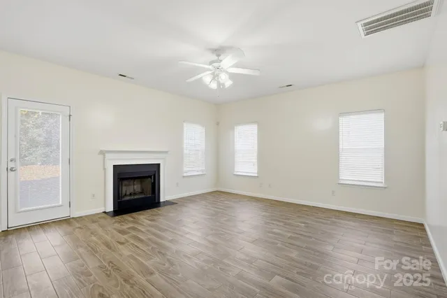 an empty room with windows and fireplace