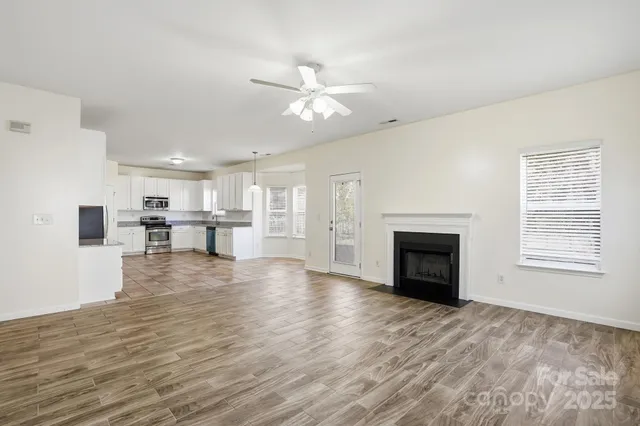 a view of a livingroom with a fireplace a ceiling fan and windows
