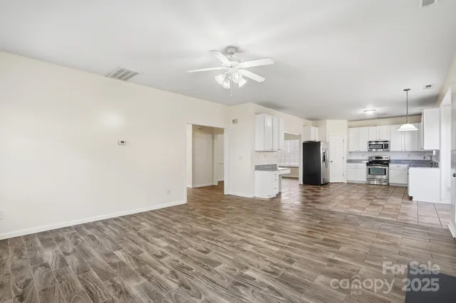 an empty room with wooden floor fireplace and windows