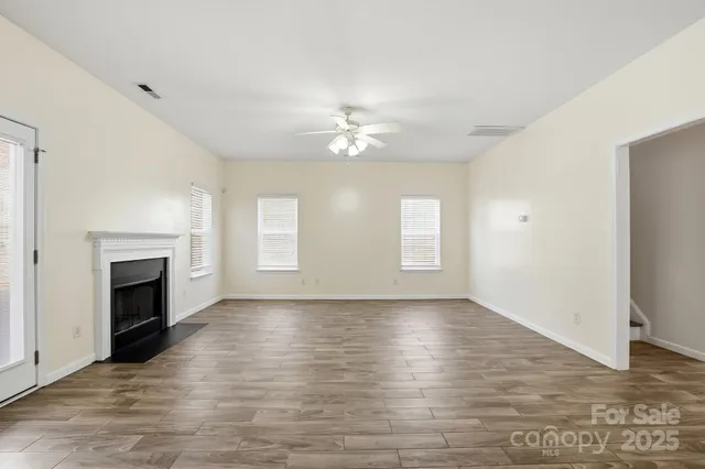 an empty room with windows and fireplace