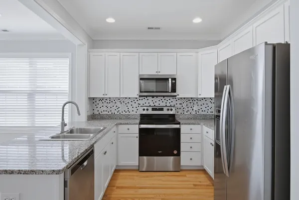 a kitchen with granite countertop a refrigerator stove and sink