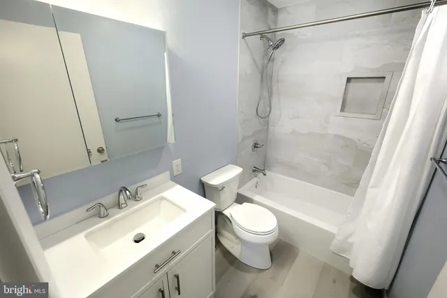 a bathroom with a bathtub shower sink vanity and mirror