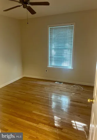 a view of empty room with window and wooden floor
