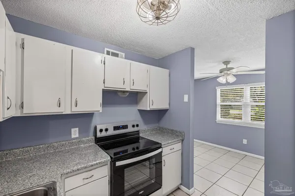 a kitchen with granite countertop a sink a stove and cabinets