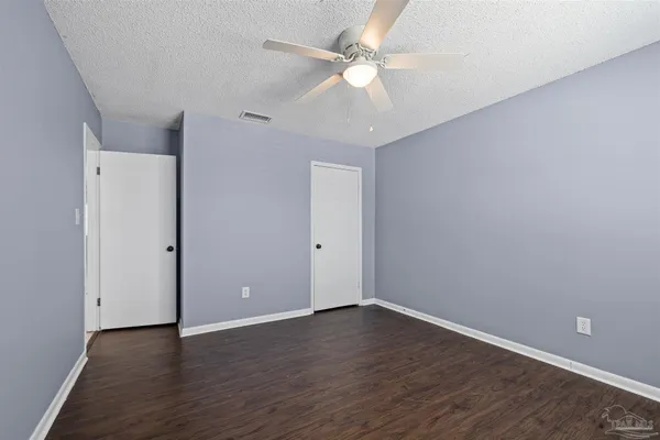 a view of an empty room with chandelier fan and wooden floor