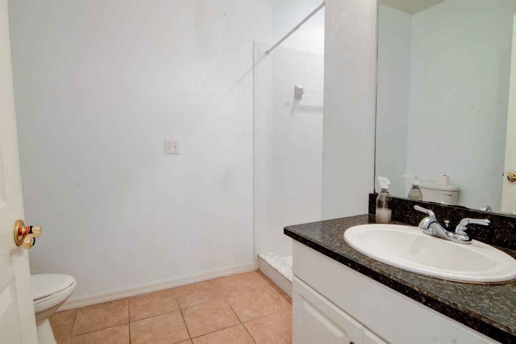 1563 Northwest 29 Road, Unit 108 Gainesville, FL 32605 - Photo 11 of 25 a bathroom with a granite countertop sink and a mirror