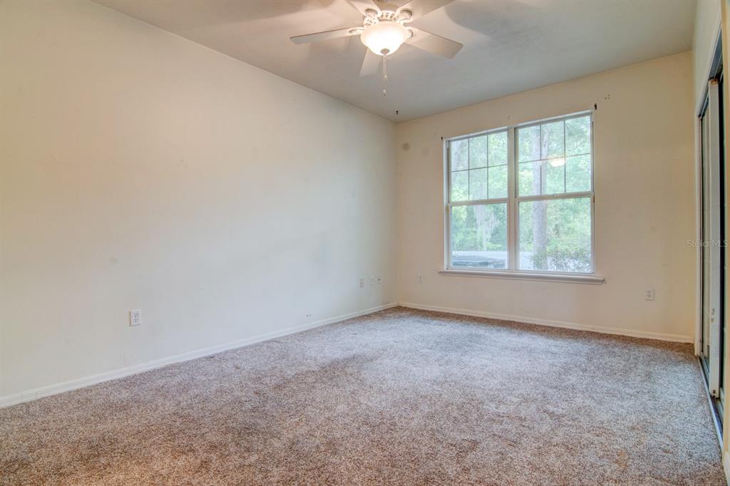 1563 Northwest 29 Road, Unit 108 Gainesville, FL 32605 - Photo 16 of 25 an empty room with a chandelier fan and windows