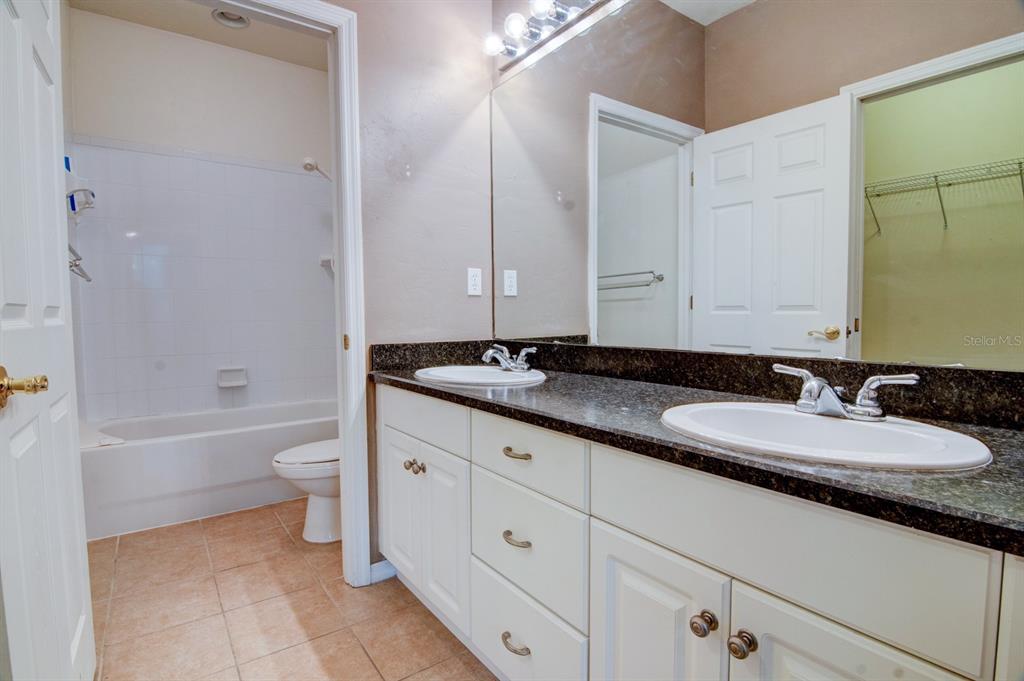 1563 Northwest 29 Road, Unit 108 Gainesville, FL 32605 - Photo 20 of 25 a bathroom with a granite countertop double vanity sink a mirror and a bathtub