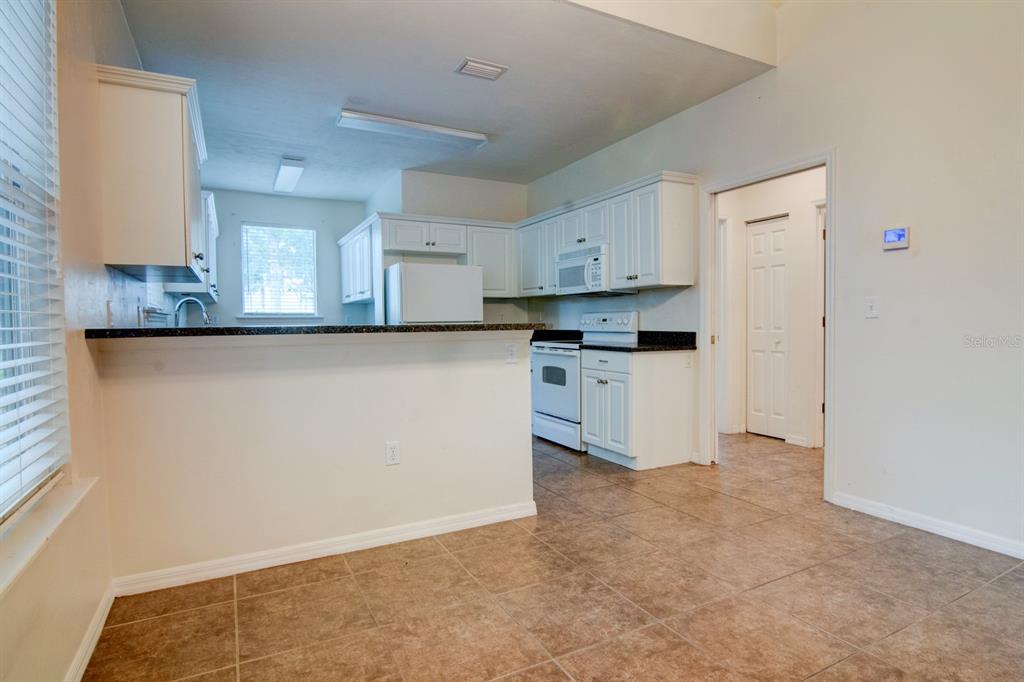 1563 Northwest 29 Road, Unit 108 Gainesville, FL 32605 - Photo 7 of 25 a kitchen with granite countertop a sink cabinets and stainless steel appliances