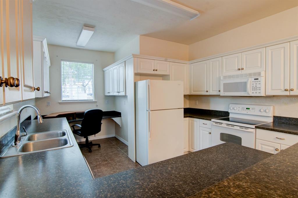 1563 Northwest 29 Road, Unit 108 Gainesville, FL 32605 - Photo 9 of 25 a kitchen with a refrigerator a stove a sink dishwasher and white cabinets with wooden floor