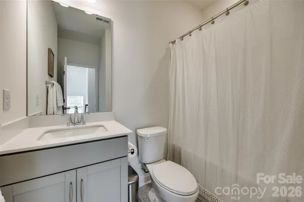 a bathroom with a sink a toilet a mirror and shower curtain