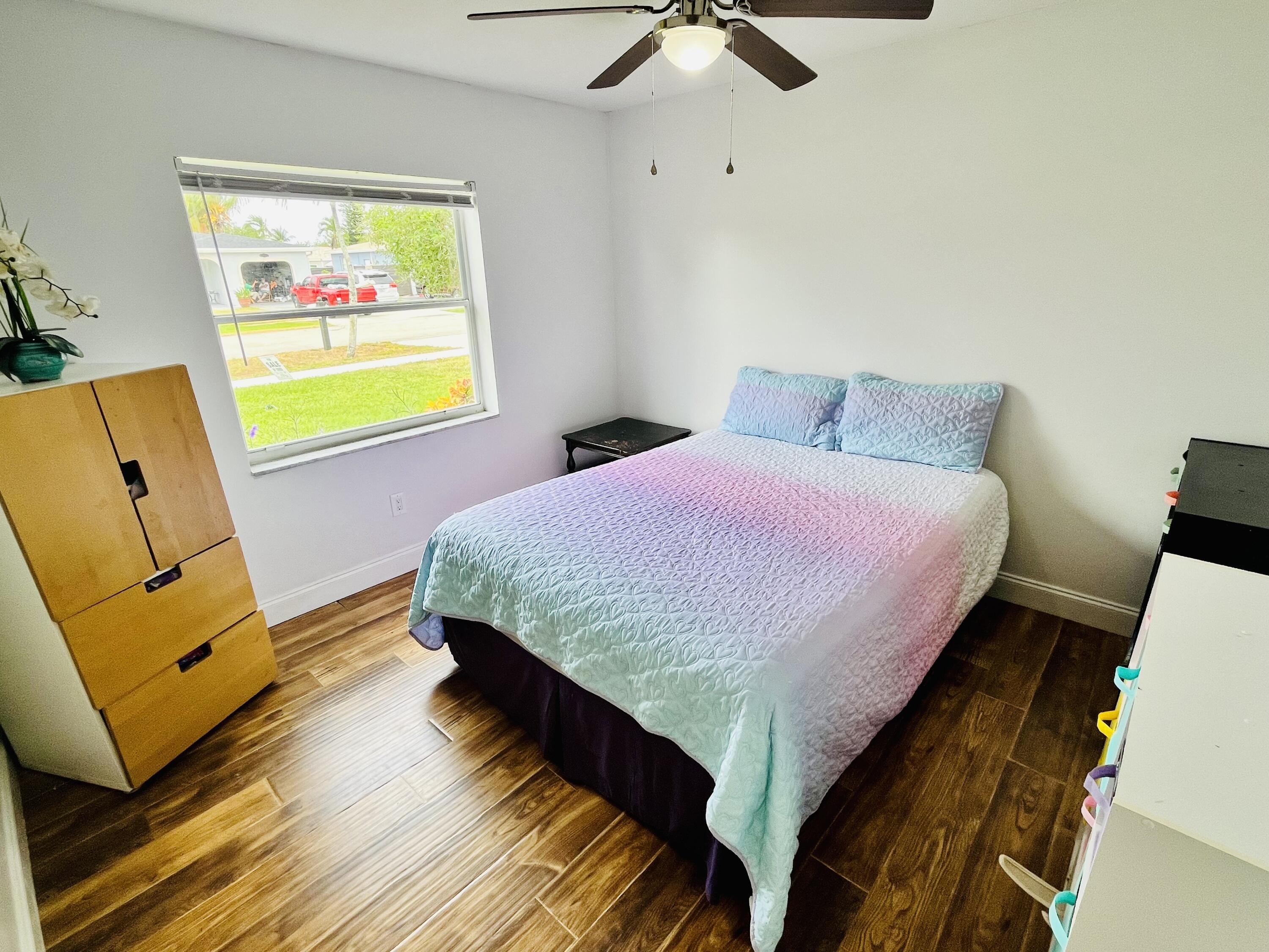 4730 Betelnut Street Boca Raton, FL 33428 - Photo 21 of 42 a bedroom with a bed and wooden floor