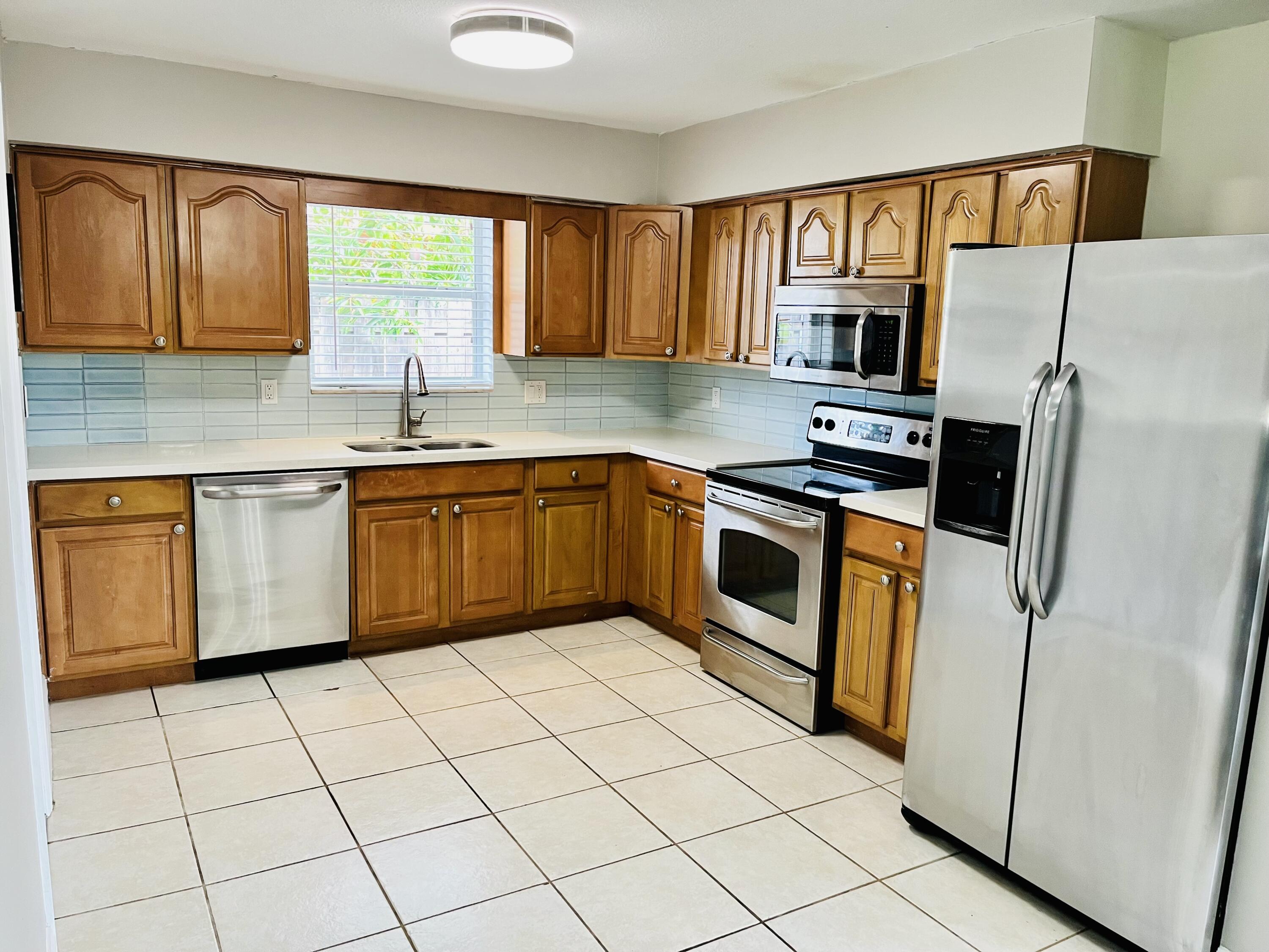 4730 Betelnut Street Boca Raton, FL 33428 - Photo 7 of 42 a kitchen with stainless steel appliances granite countertop a stove sink and refrigerator