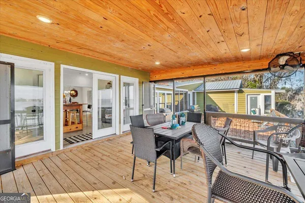 a view of a dining room and livingroom with furniture wooden floor kitchen view and a chandelier