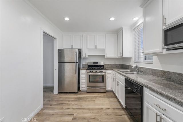 a kitchen with stainless steel appliances granite countertop a refrigerator a stove top oven a sink and dishwasher