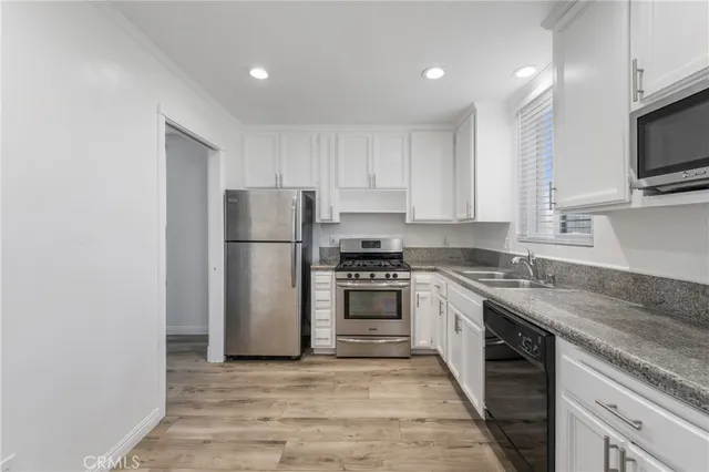 a kitchen with stainless steel appliances granite countertop a refrigerator a stove top oven a sink and dishwasher