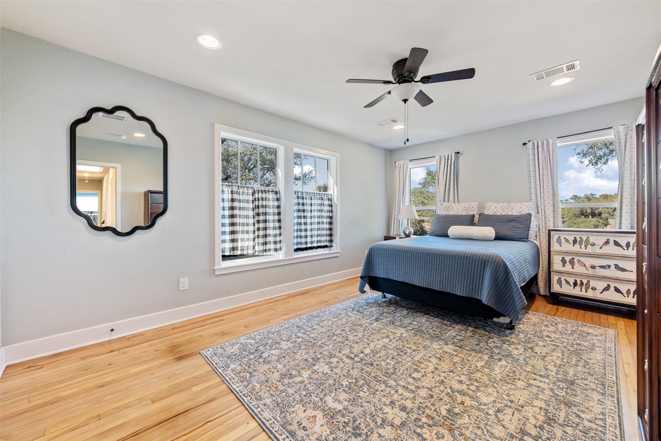 1610 Pace Bend Road North Spicewood, TX 78669 - Photo 23 of 32 a spacious bedroom with a bed a mirror and a large window