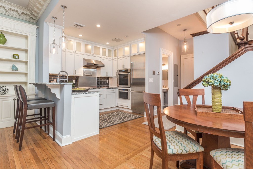 193 Beacon Street, Unit 4 Boston, MA 02116 - Photo 7 of 22 a kitchen with stainless steel appliances kitchen island granite countertop a dining table chairs and a refrigerator