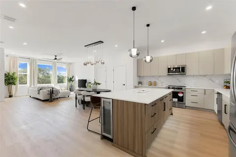 a large white kitchen with lots of counter space a sink appliances and cabinets
