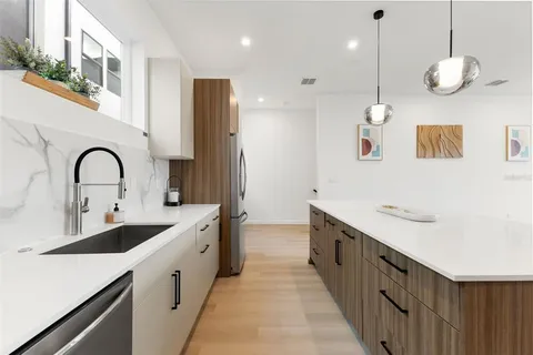 a kitchen with stainless steel appliances kitchen island a table chairs in it and white cabinets