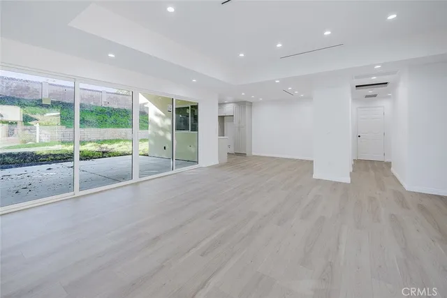 a view of an empty room with wooden floor and windows