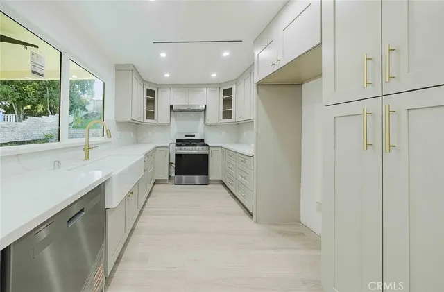 a large white kitchen with a sink stainless steel appliances and cabinets