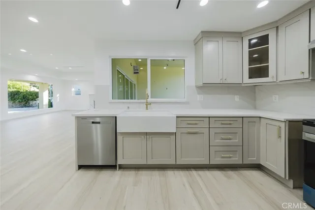 a kitchen with stainless steel appliances granite countertop a sink and cabinets with wooden floor