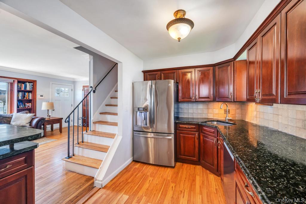398 33rd Street Lindenhurst, NY 11757 - Photo 22 of 44 a kitchen with granite countertop wooden floors wooden cabinets a refrigerator and a sink