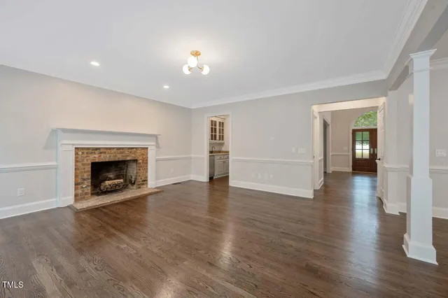 a view of an empty room with wooden floor fireplace and a window