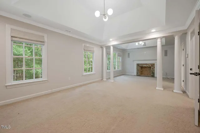 an empty room with windows and fireplace