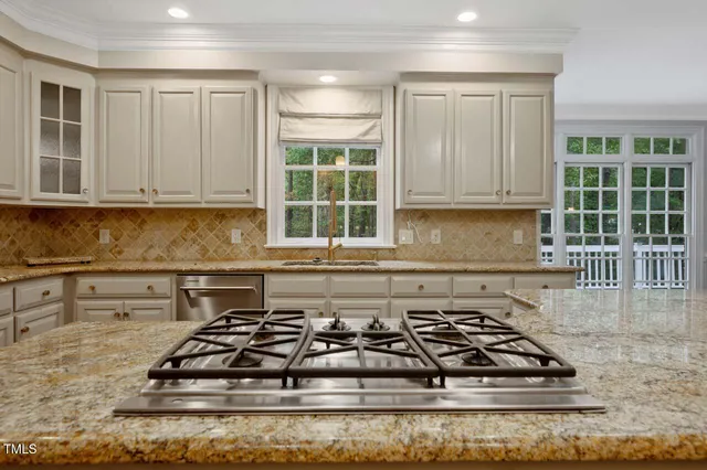 a kitchen with granite countertop a stove a sink and white cabinets