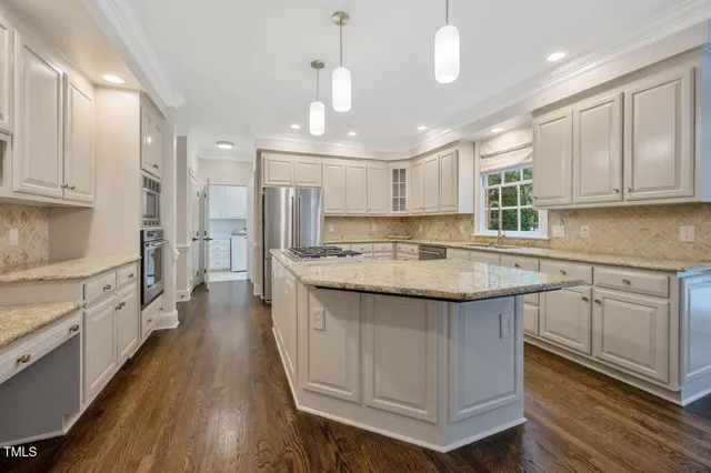 a kitchen with kitchen island granite countertop a sink a counter space appliances and cabinets