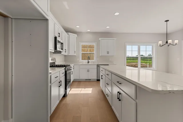 a kitchen with kitchen island granite countertop a stove a sink a center island and windows