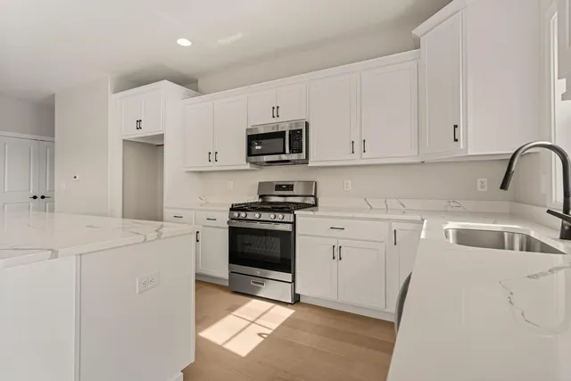 a large white kitchen with granite countertop a large window and a sink