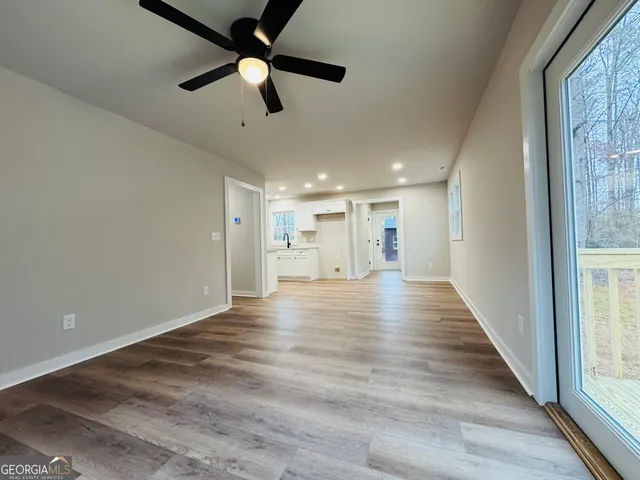 a view of a hallway with wooden floor and a ceiling fan