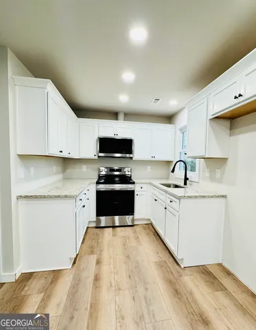 a kitchen with granite countertop white cabinets and white appliances
