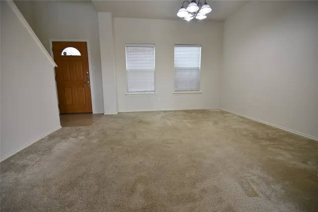 an empty room with chandelier fan and windows