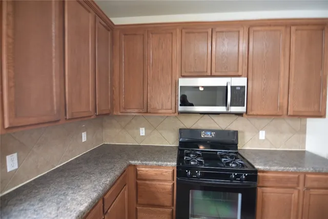 a kitchen with granite countertop a stove top oven cabinetry and garage