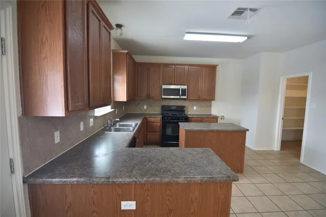 a kitchen with stainless steel appliances granite countertop a sink a stove a microwave a counter top and a stove