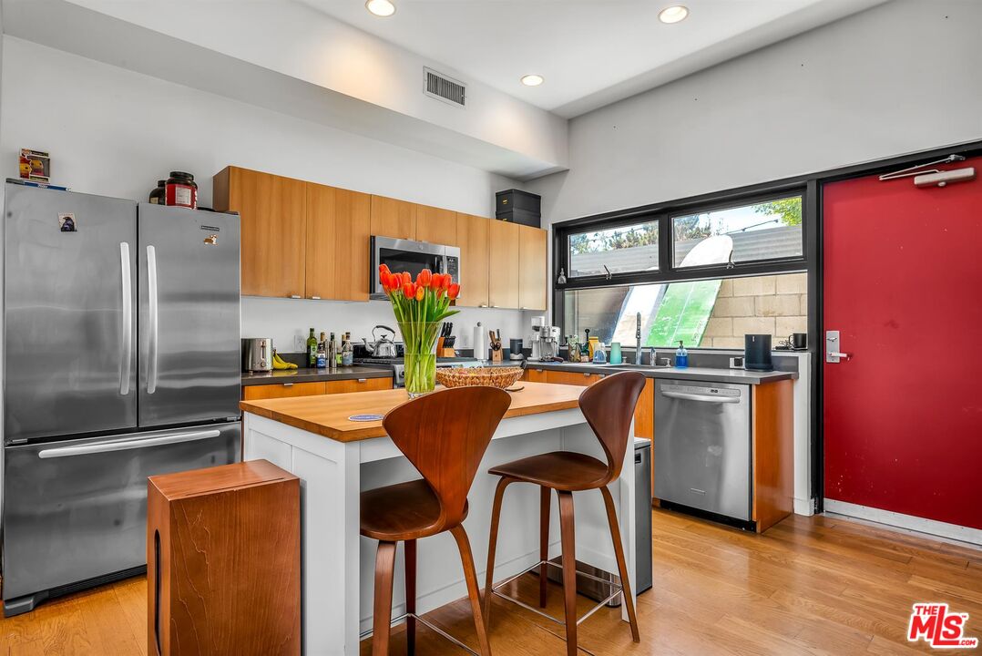815 Hampton Drive, Unit 5B Venice, CA 90291 - Photo 8 of 20 a kitchen with stainless steel appliances granite countertop a refrigerator a stove and a dining table with wooden floor