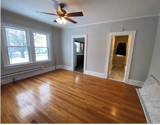 a view of an empty room with window and wooden floor