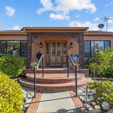 a view of a building with potted plants and a large tree