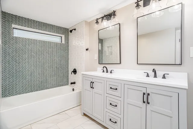 a bathroom with a double vanity sink mirror and bathtub