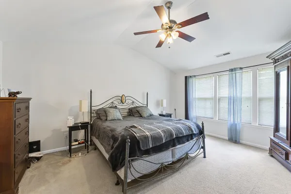 a spacious bedroom with a bed a window and a chandelier